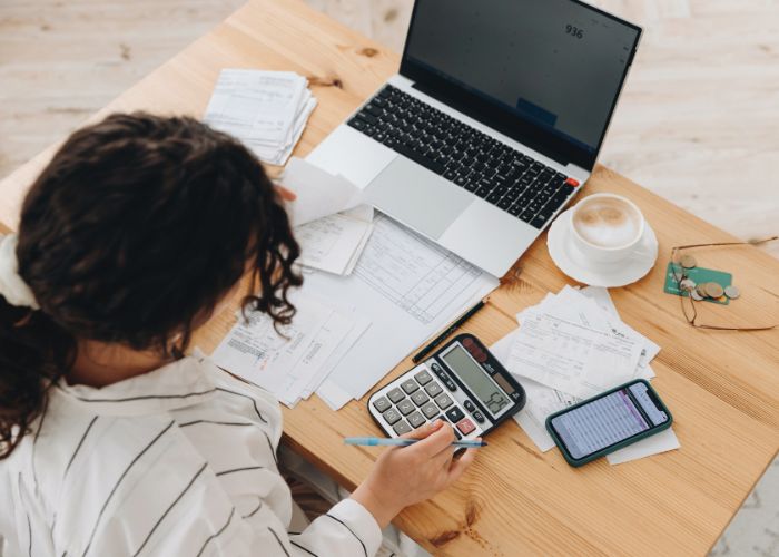 woman sitting at table with laptop, calculator doing company accounts